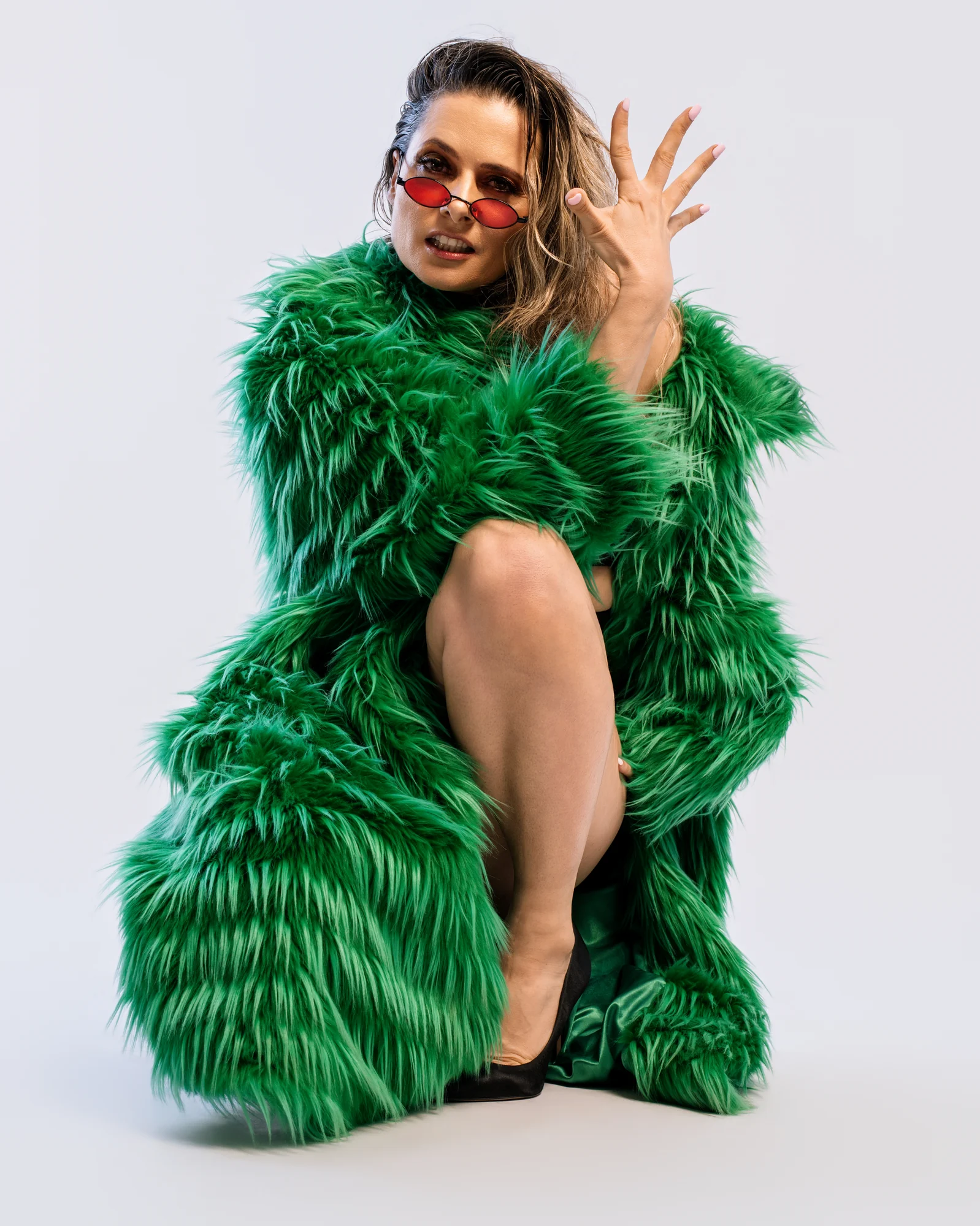 Portrait en studio, manteau vert et lunettes rouges.