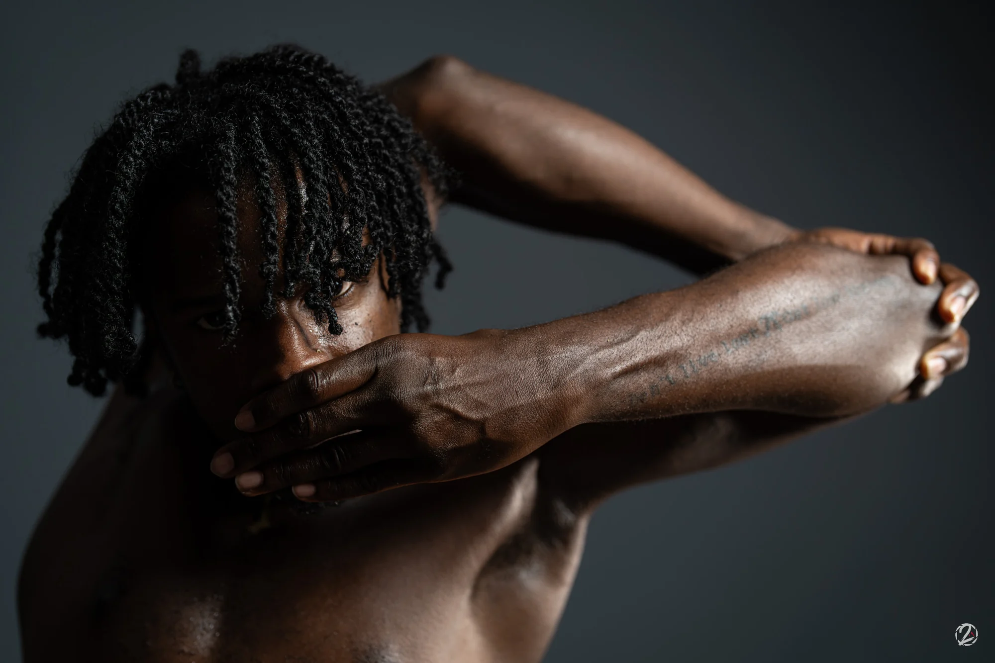 Portrait en studio, bras croisés devant le visage.