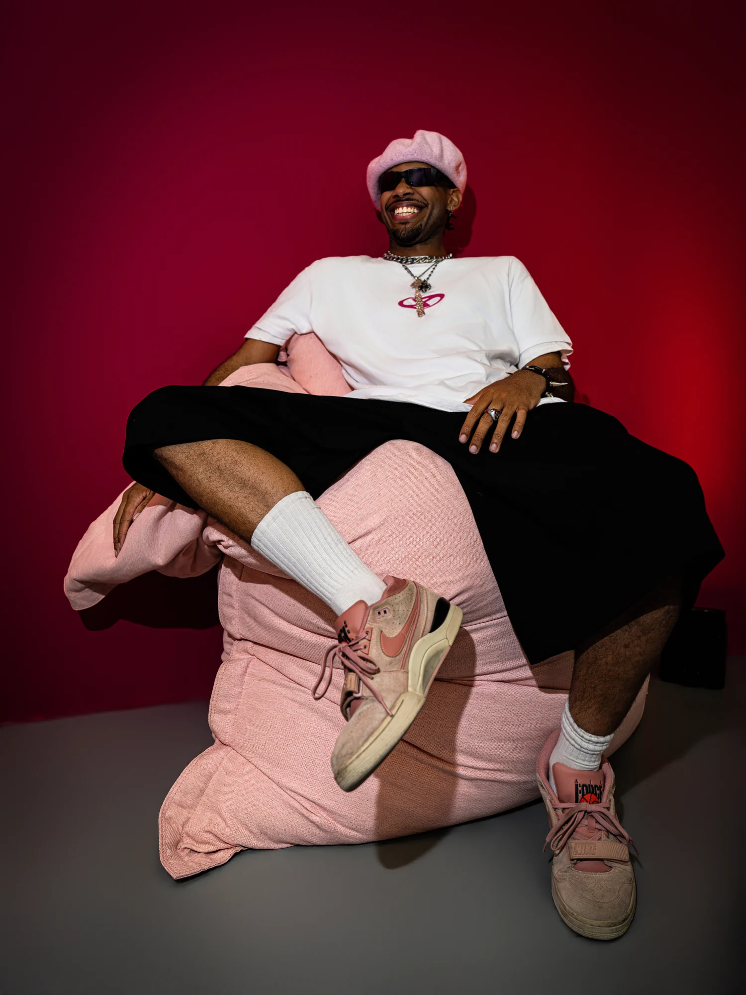 Portrait assis sur un fauteuil rose, sur fond rouge.